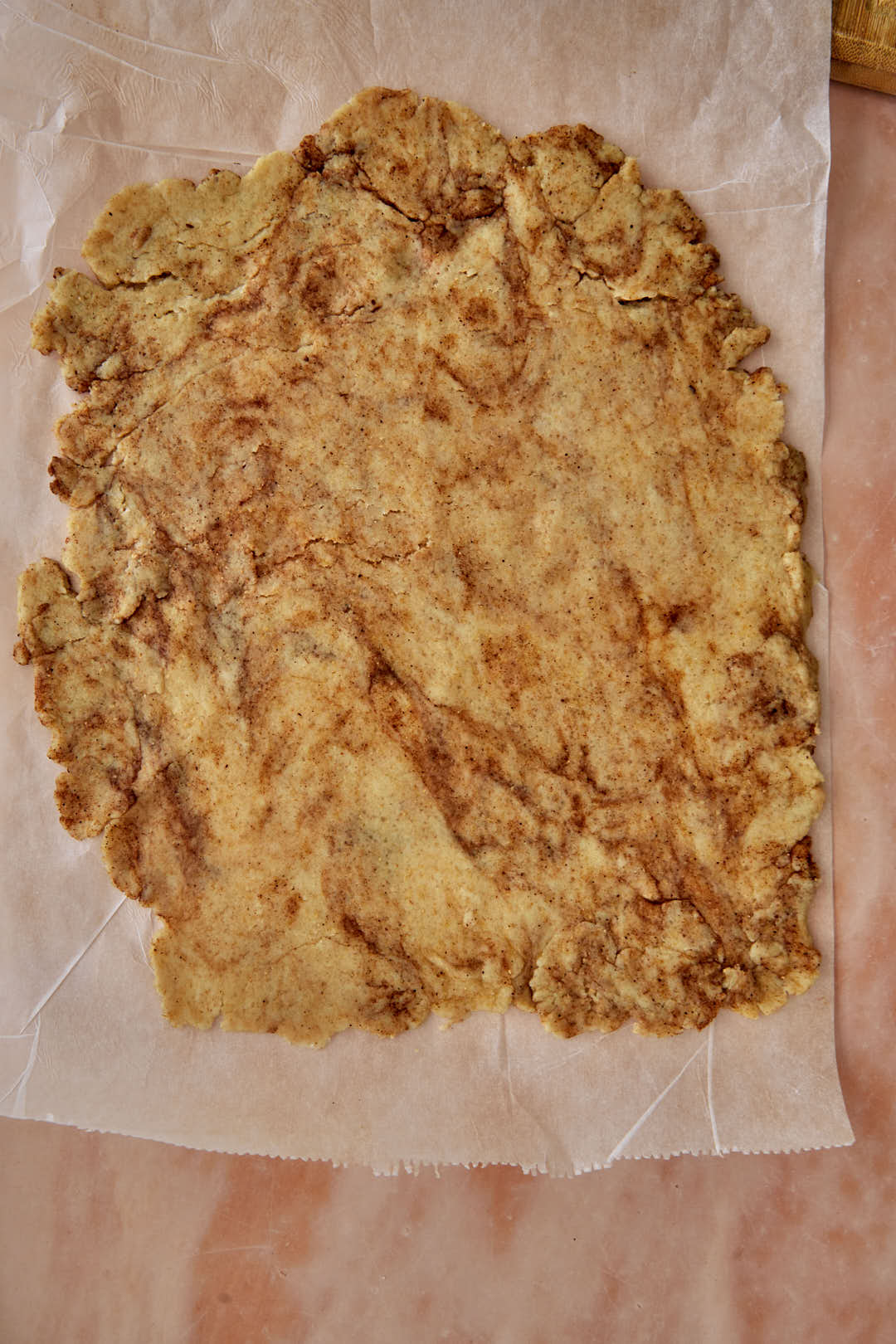 cinnamon toast crunch dough rolled out onto parchment paper.