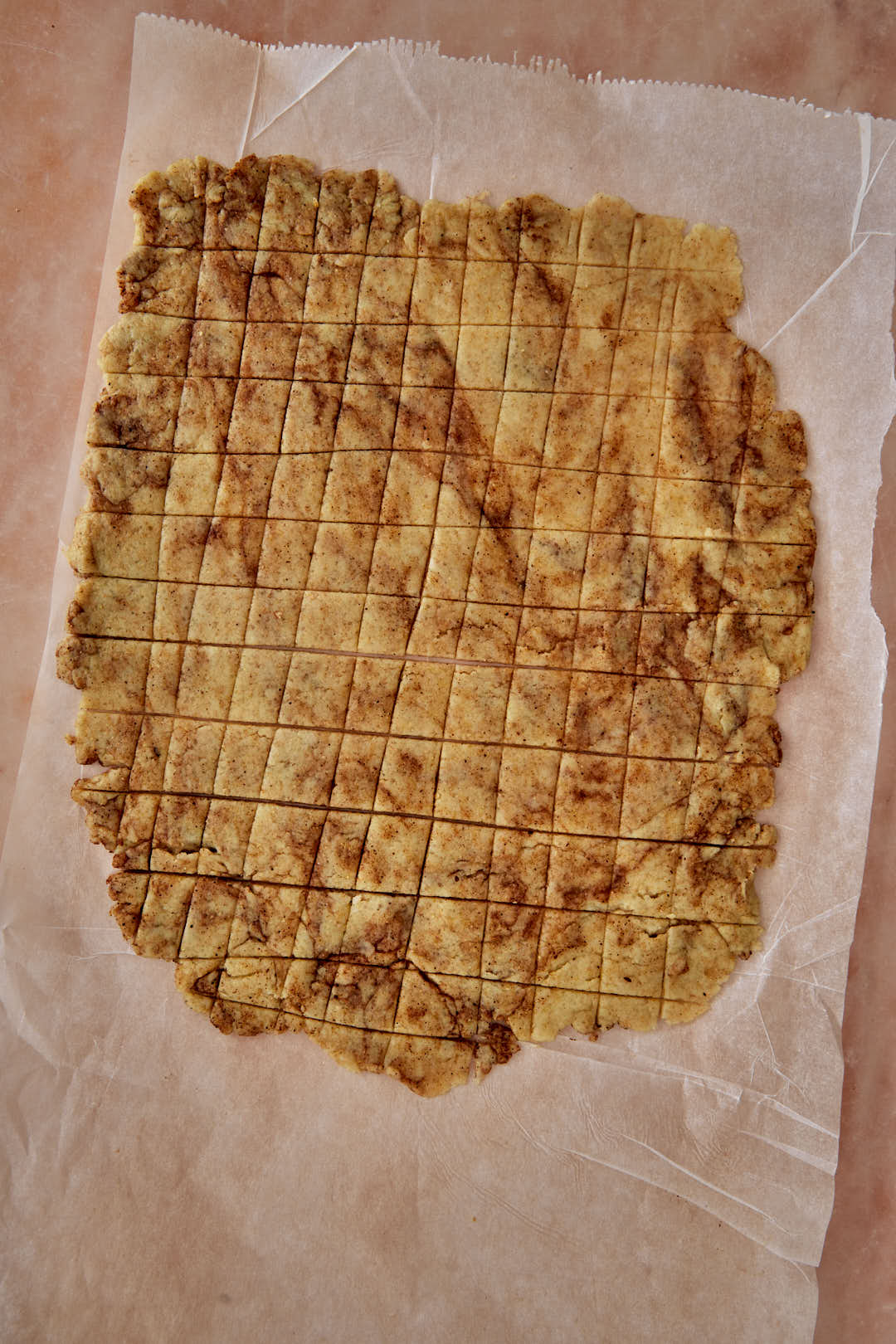 squares cut into cinnamon toast crunch dough on parchment paper.