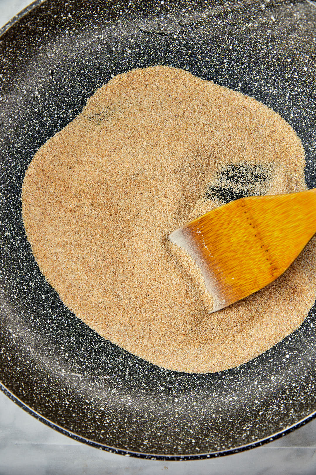 toasted semolina in a large skillet with a wooden spatula