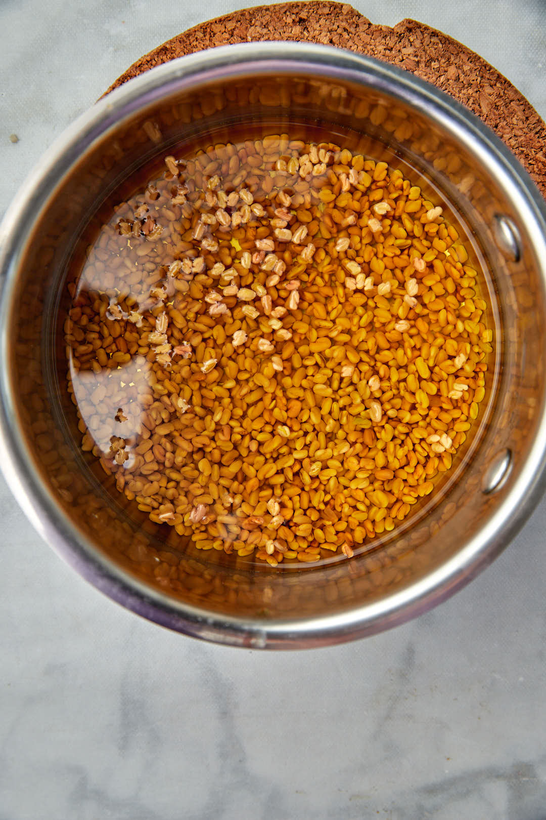 fenugreek seeds in water in a saucepan.
