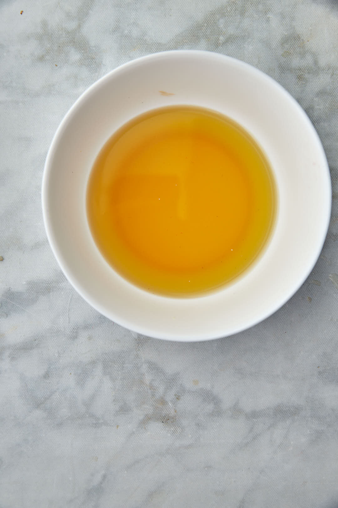 strained fenugreek water in a white bowl.
