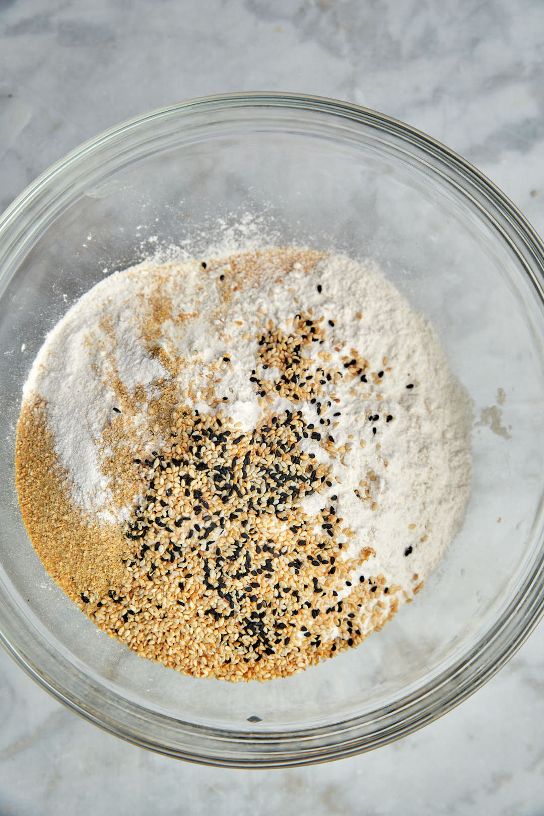 semolina, flour, and sesame seeds in a glass bowl.