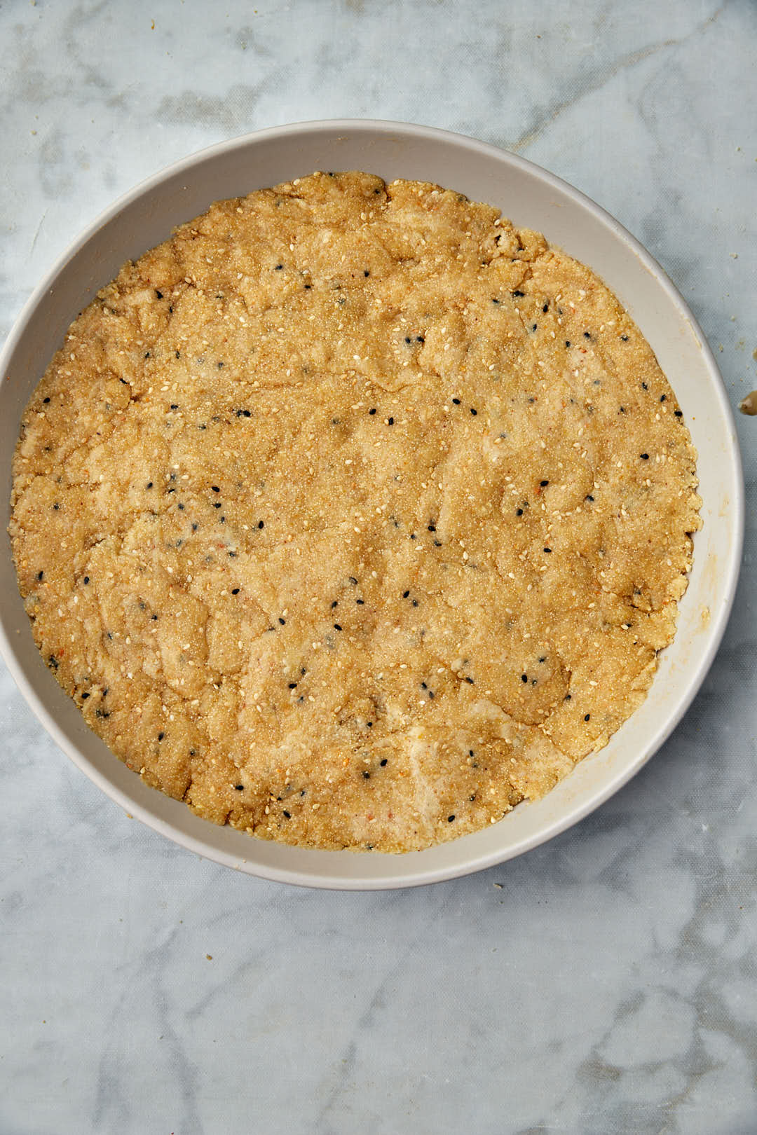 hilbeh dough pressed into circular pan.