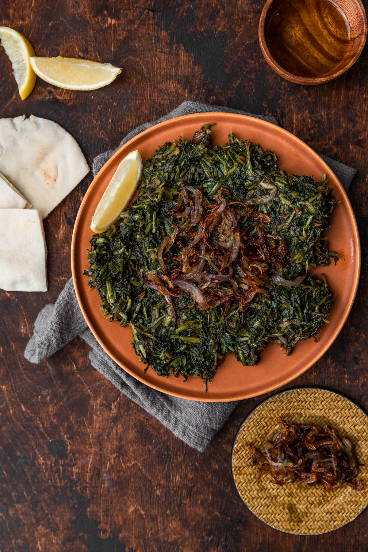 sauteed greens on a background with extra pita bread and caramelized onions.