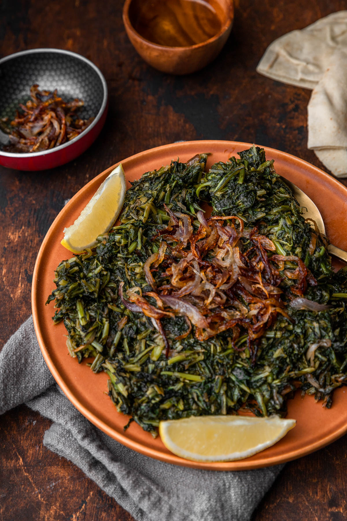 sauteed dandelion greens with lemon wedges on the plate and extra caramelized onions in a small bowl.