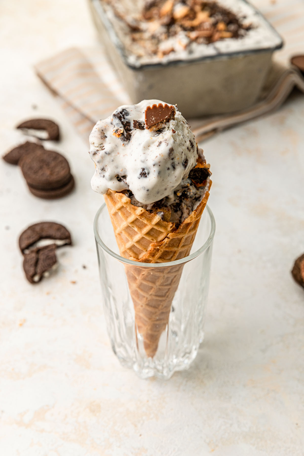 Oreo ice cream cone in a glass with Oreo's in the background.