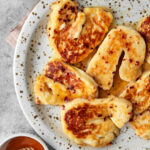 a close up photo of sliced grilled halloumi in a hot honey sauce on a white plate.