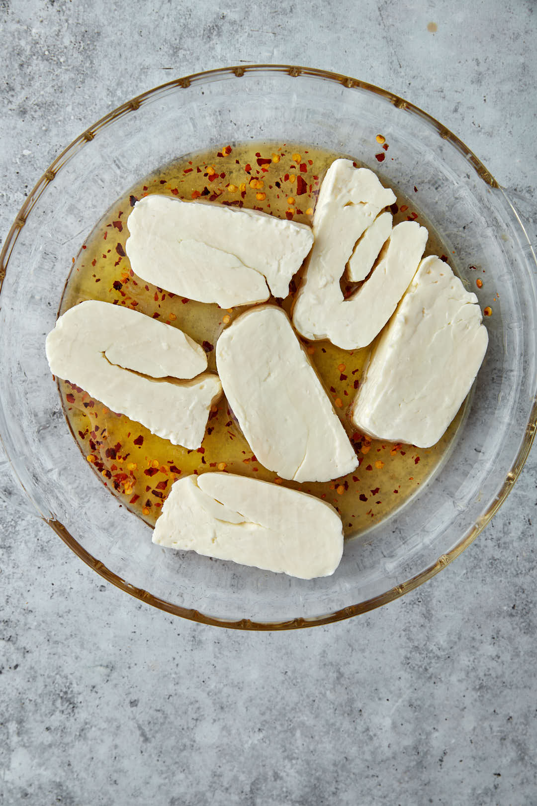 slices of halloumi on hot honey sauce in a glass bowl.