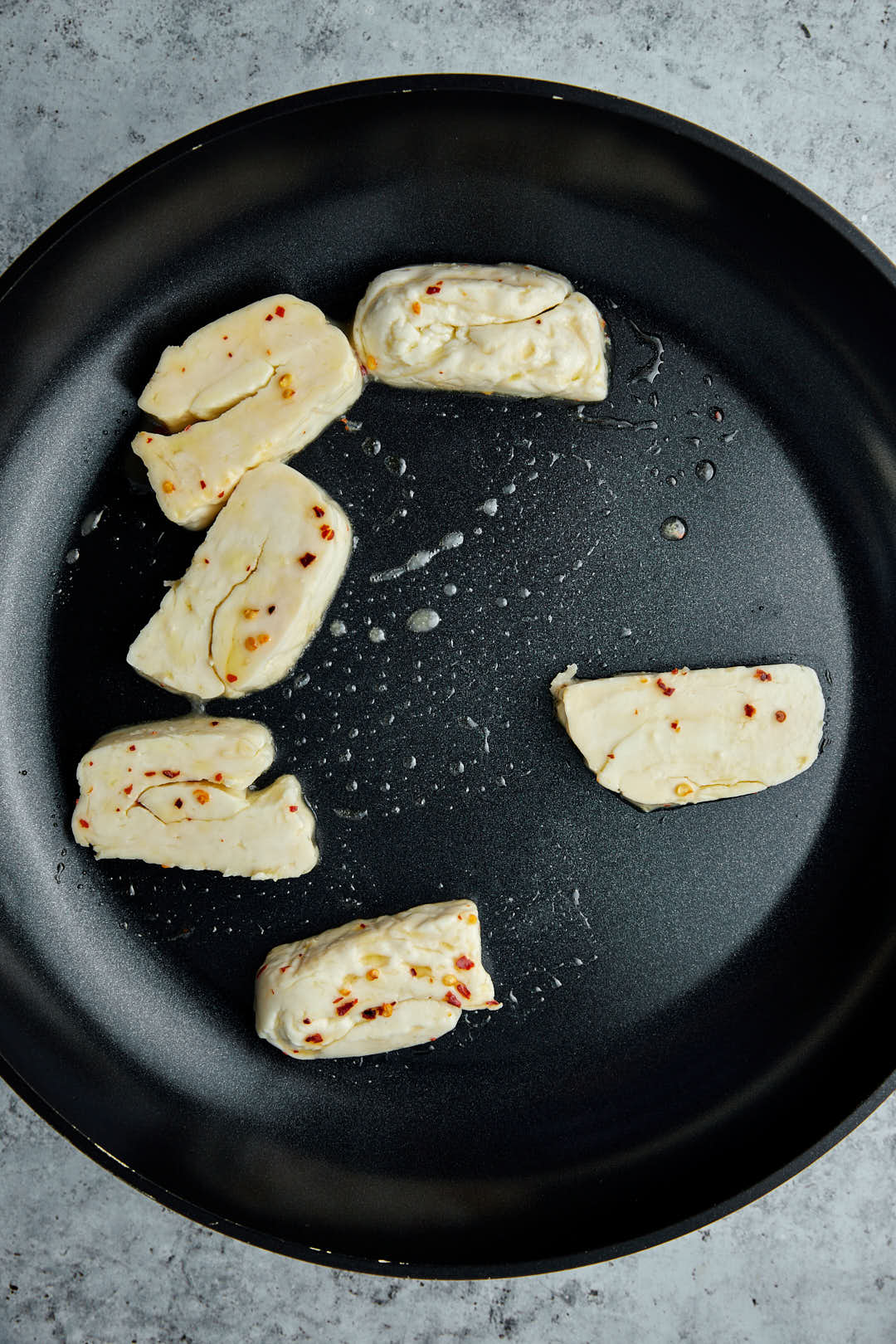 halloumi slices in a skillet being grilled.