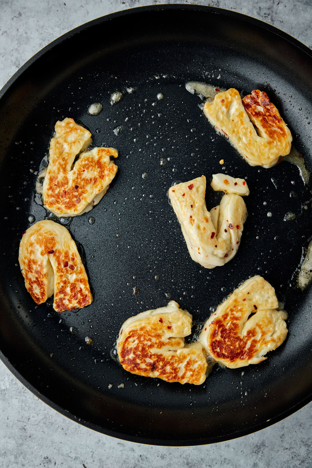 grilled halloumi slices in a black skillet.