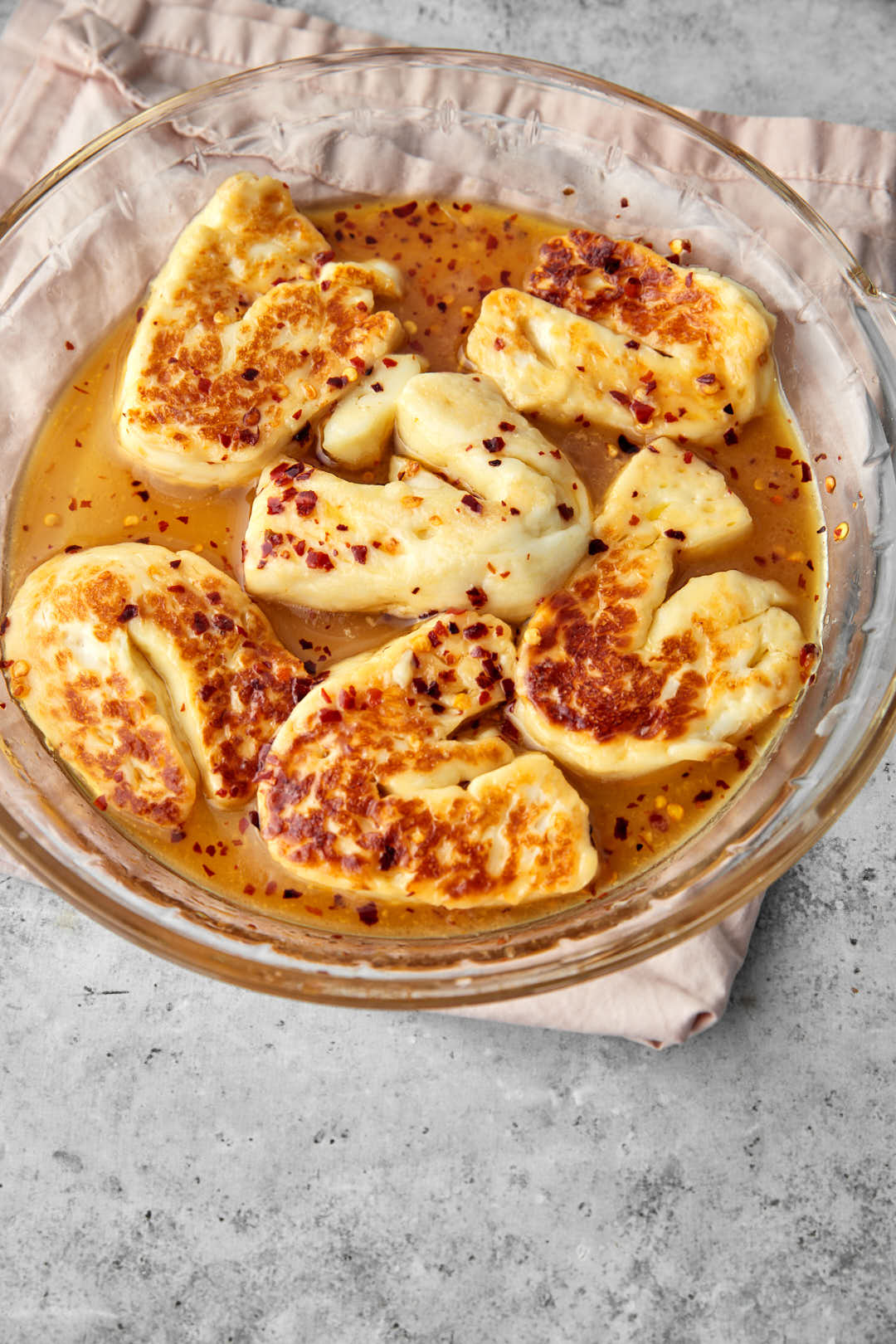hot honey halloumi in a glass pyrex dish on a pink linen towel.