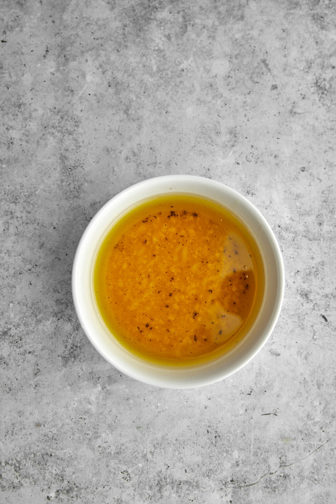 Salad dressing ingredients in a small white bowl after mixing.