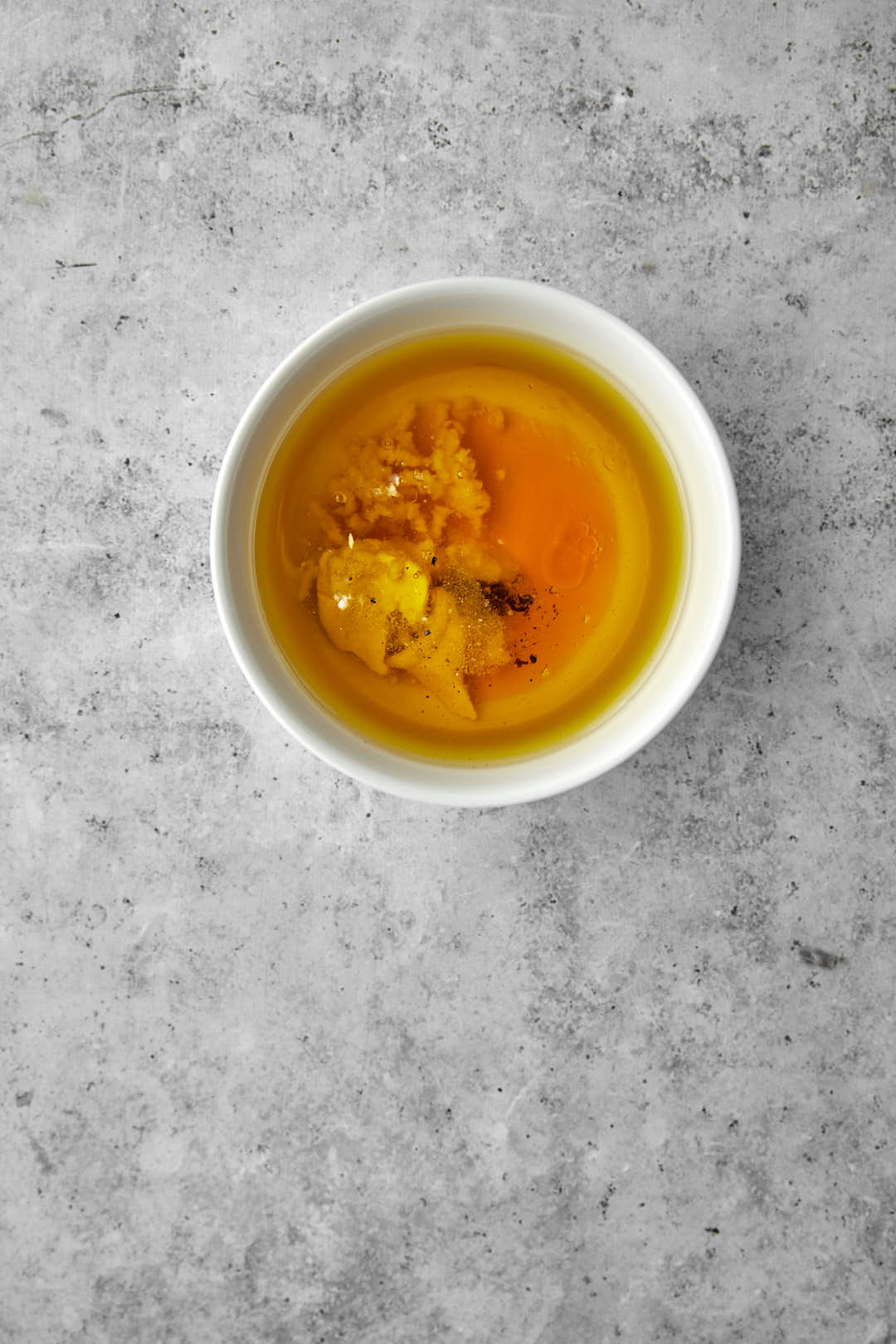 Salad dressing ingredients in a small white bowl before mixing.