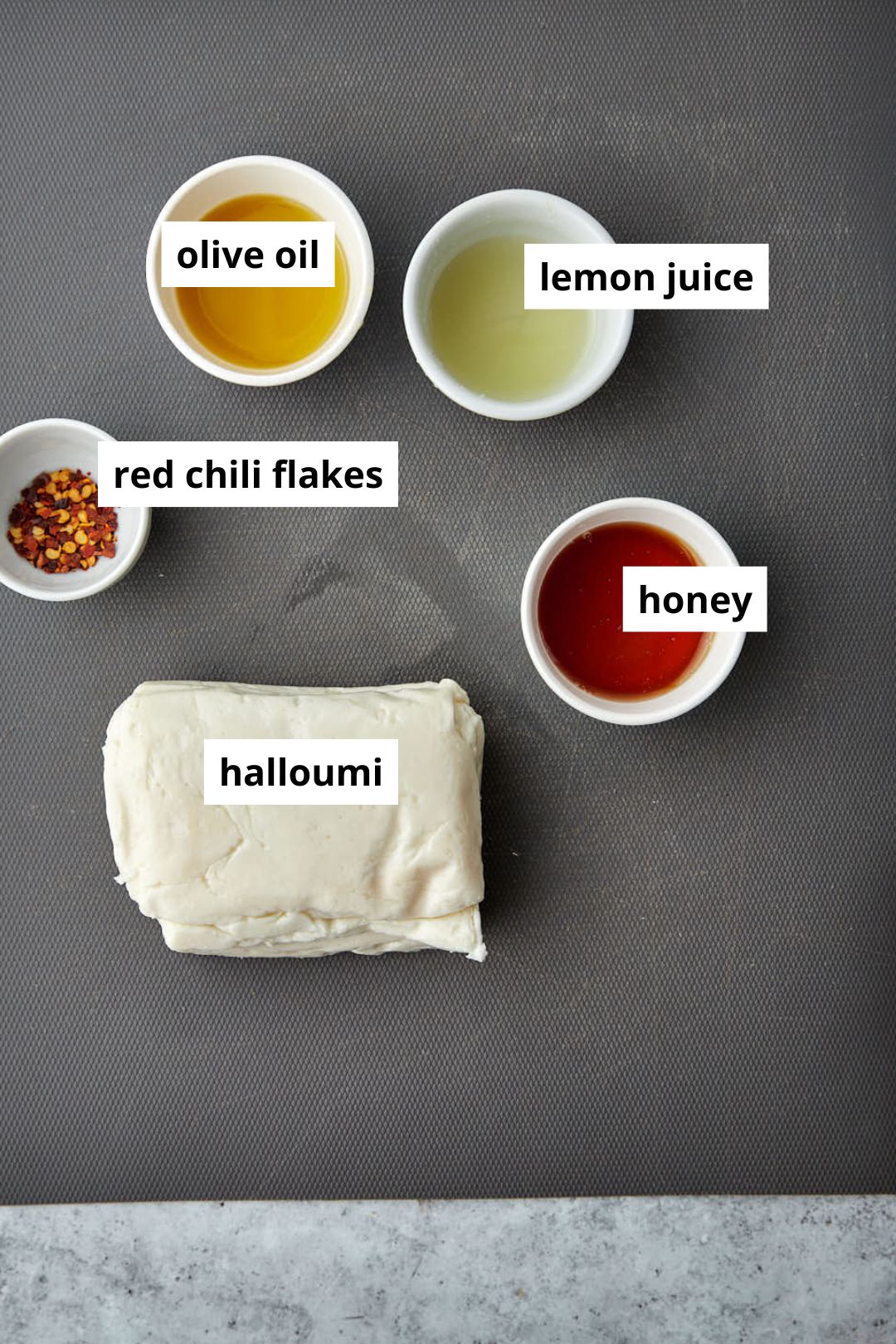 ingredients needed to make h ot honey halloumi on a gray chopping board.