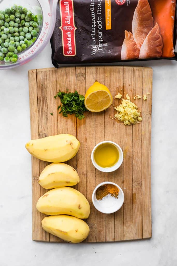 ingredients needed to make potato empanadas on a wooden cutting board