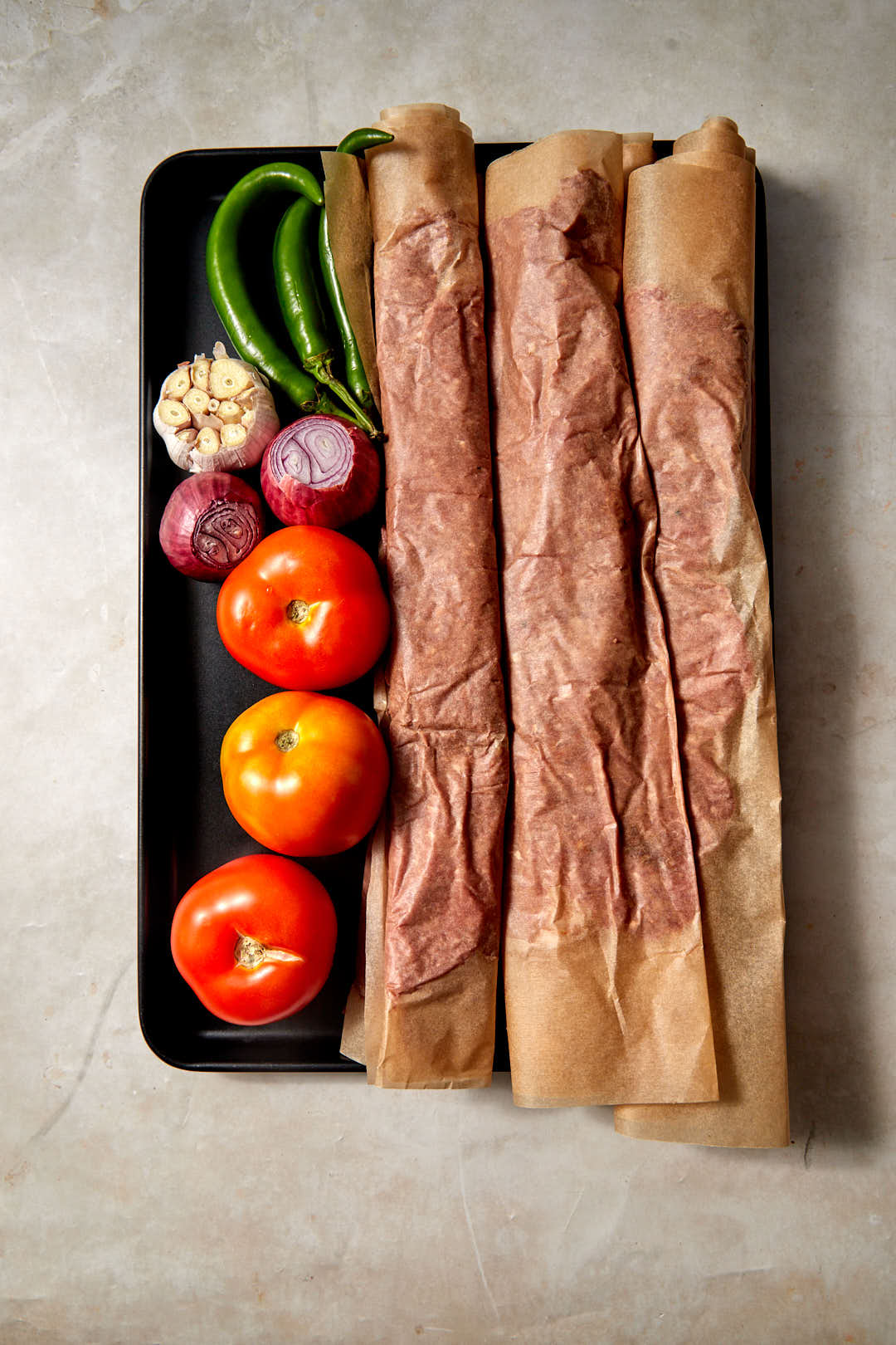 stacks of parchment paper kebab and vegetables on a baking sheet.