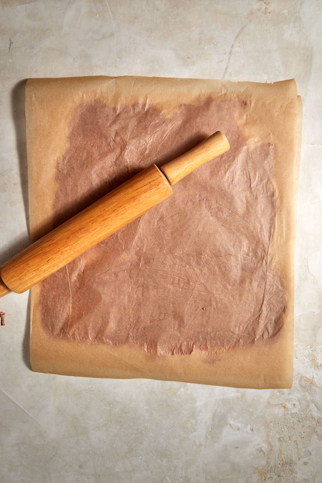 rolling pin on top of parchment paper covering doner kebab meat.
