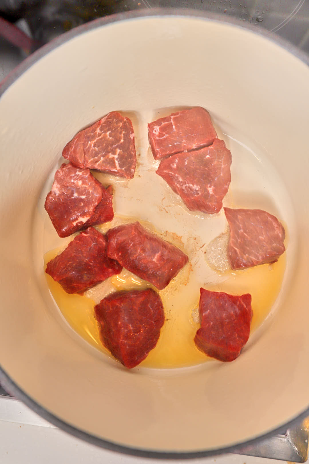 Beef cubes browning in a pan.