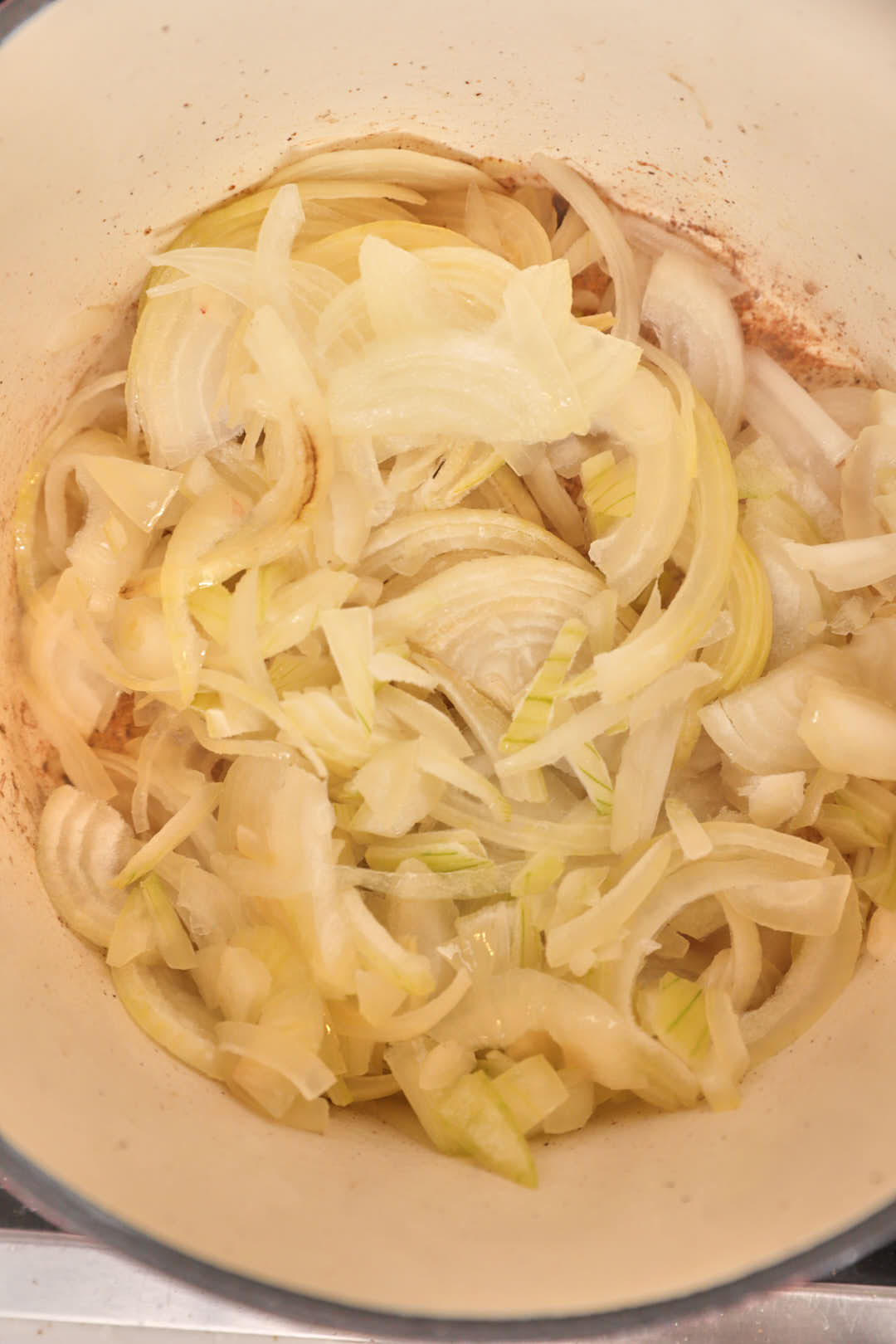 Sliced yellow onions added to a hot pan.