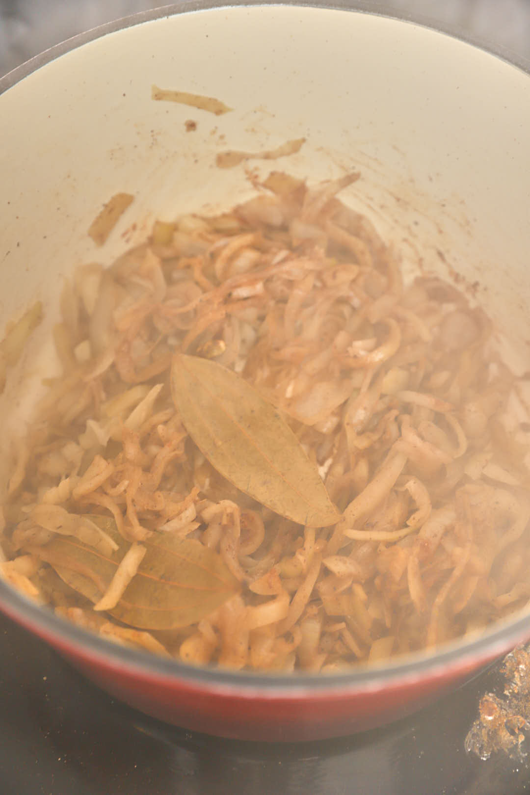 Yellow sauteed onions being stirred in a smoky hot pan.