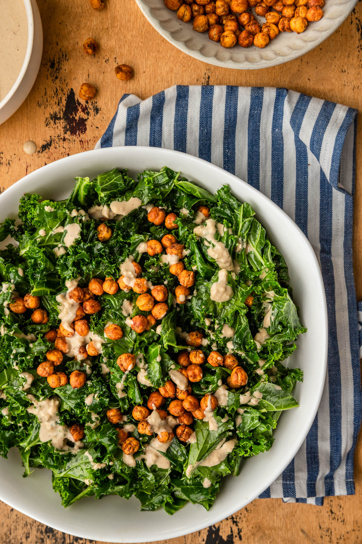 close up photo of kale chickpea salad on a blue striped kitchen towel.