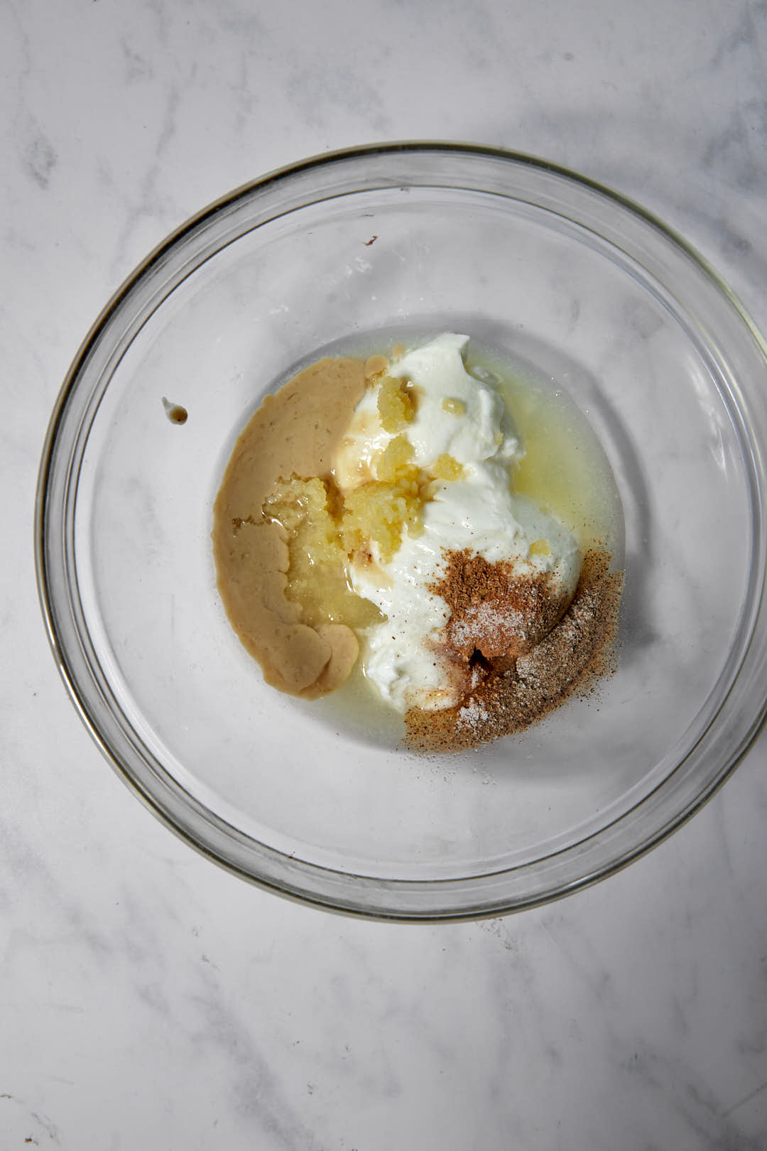 ingredients for tahini sauce in a clear glass bowl.