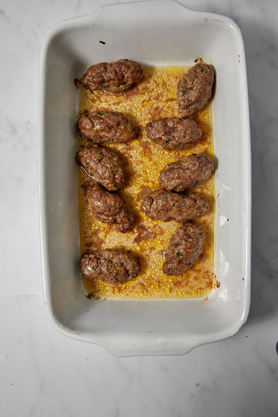 baked kofta patties in white pyrex dish.