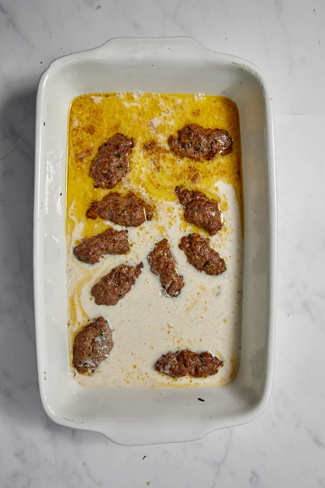 tahini sauce added to the pan with the cooked kofta patties.