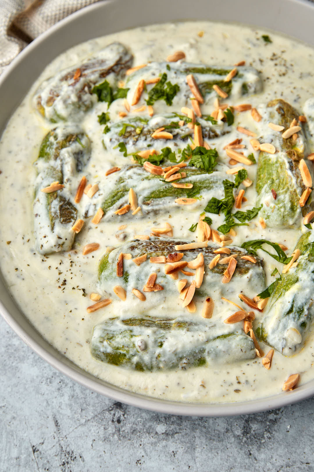 Close up photo of stuffed zucchini in yogurt sauce with toasted almond slivers