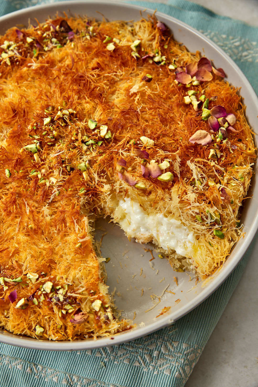 kunafa with cream with a slice taken out.