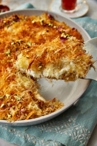 a slice of cream kunafa being lifted out of a cake pan.