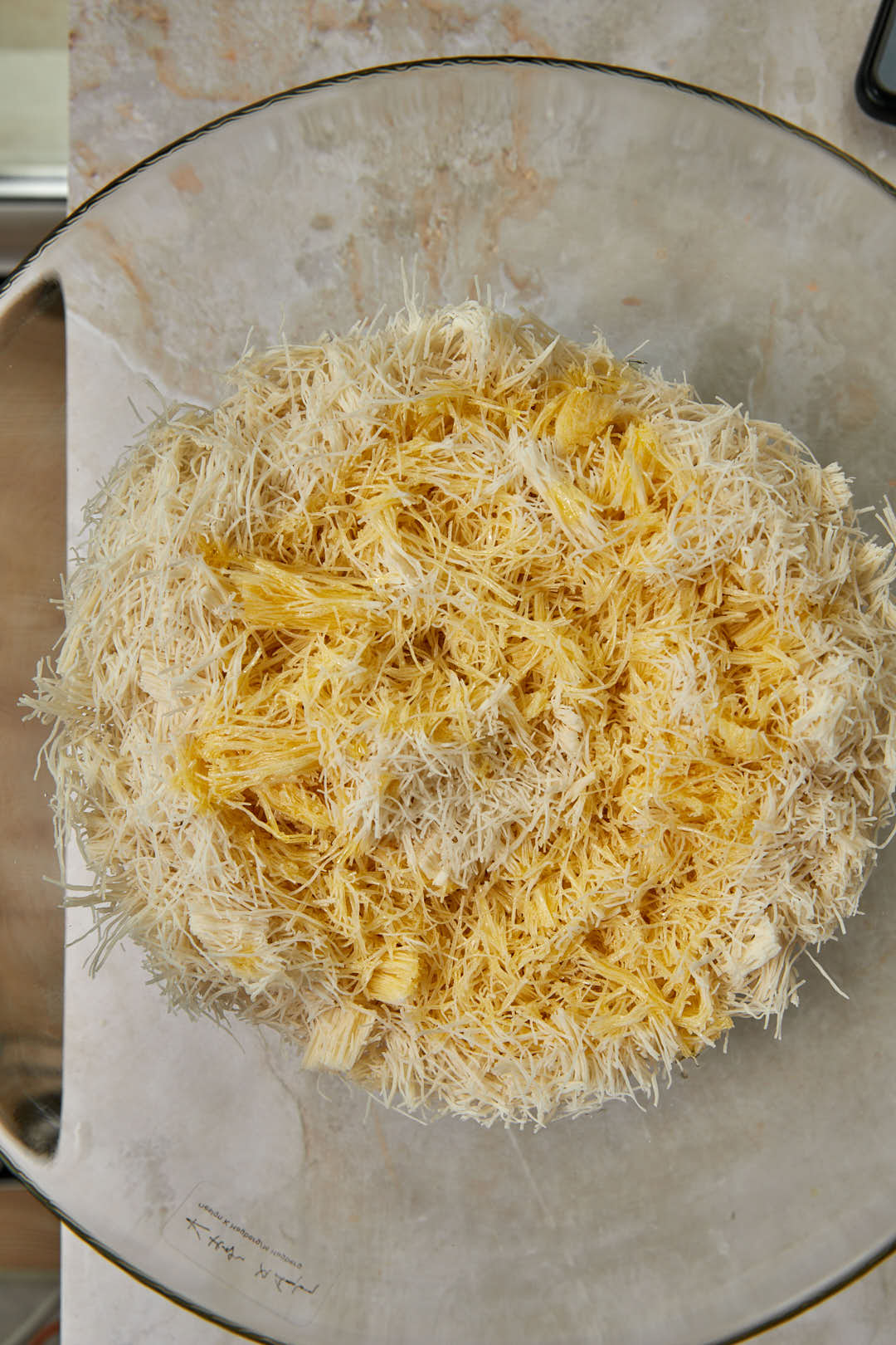 Melted ghee drizzled onto kunafa dough.