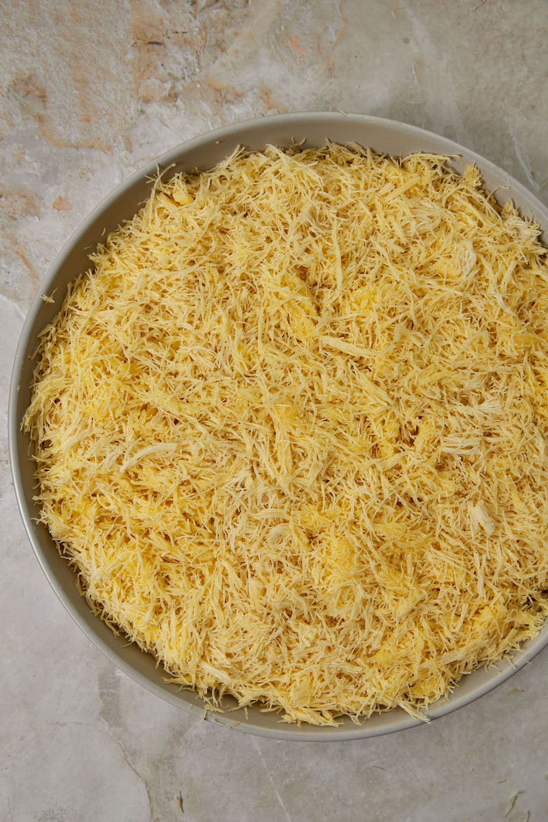 kunafa dough topped cream in a pan.