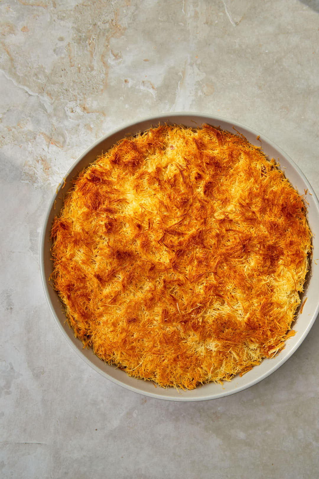 Golden brown baked cream kunafa on a light background.
