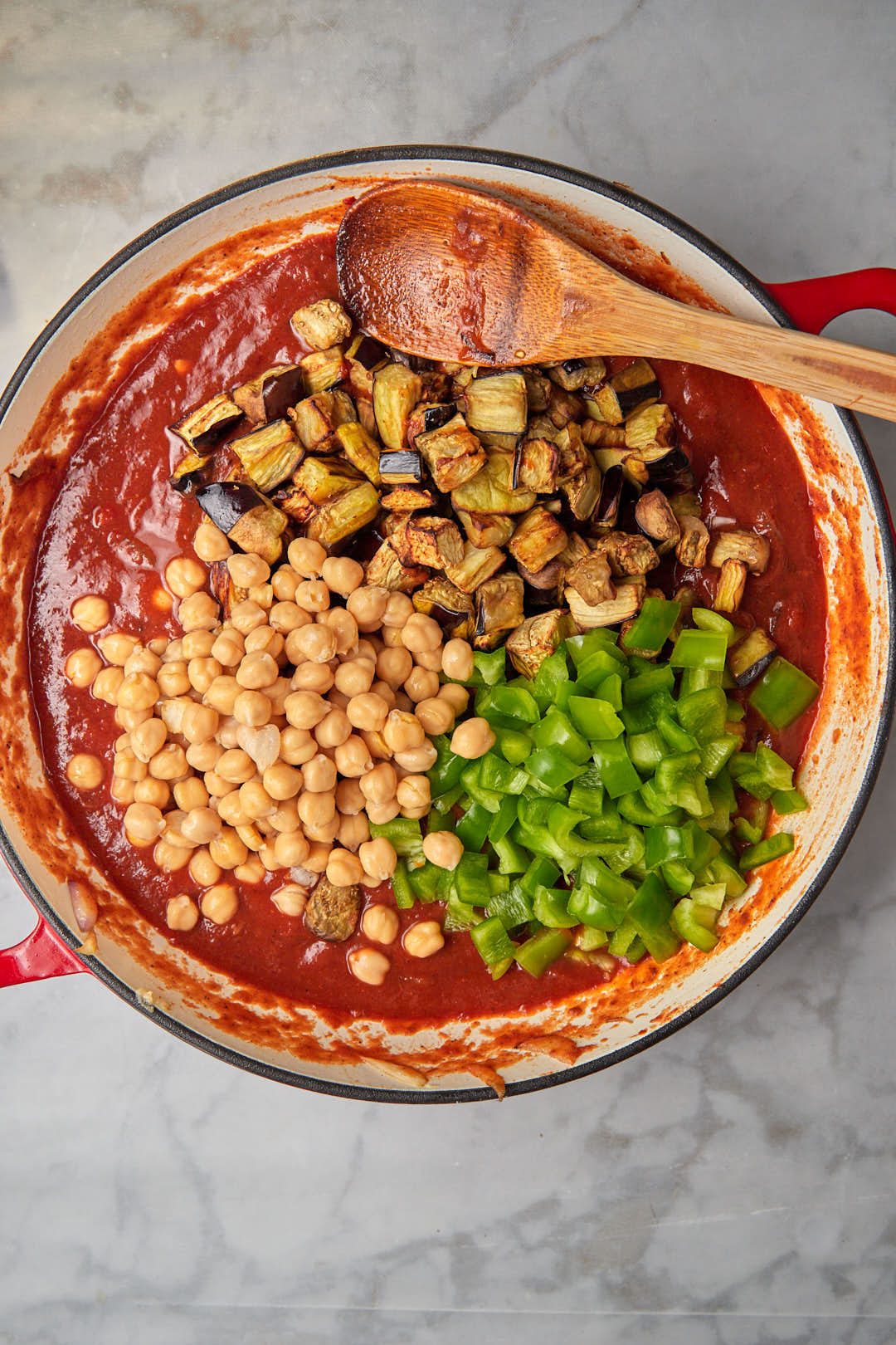 chickpeas, bell pepper and eggplant cubes in tomato sauce in a skillet.