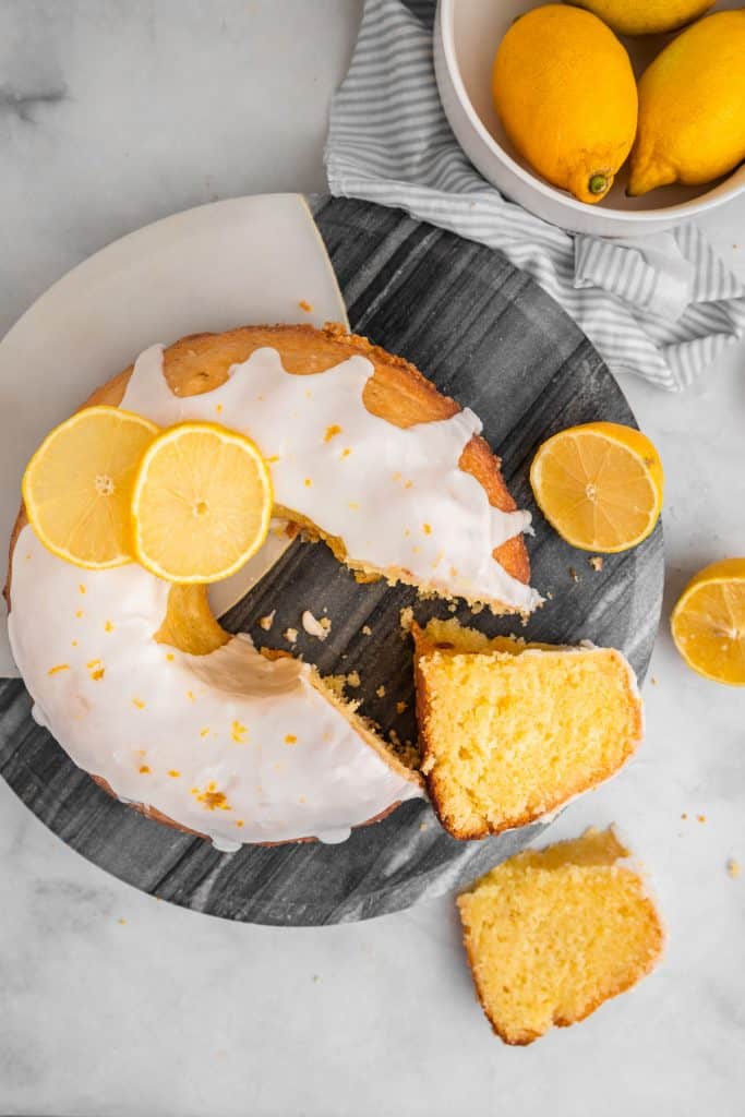 lemon cake with slices cut out and lemons
