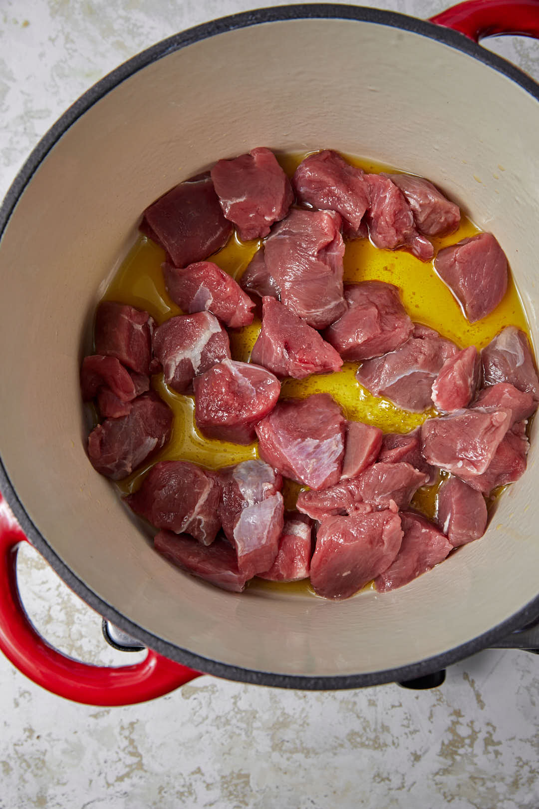 beef cubes added to olive oil in a deep saucepan.