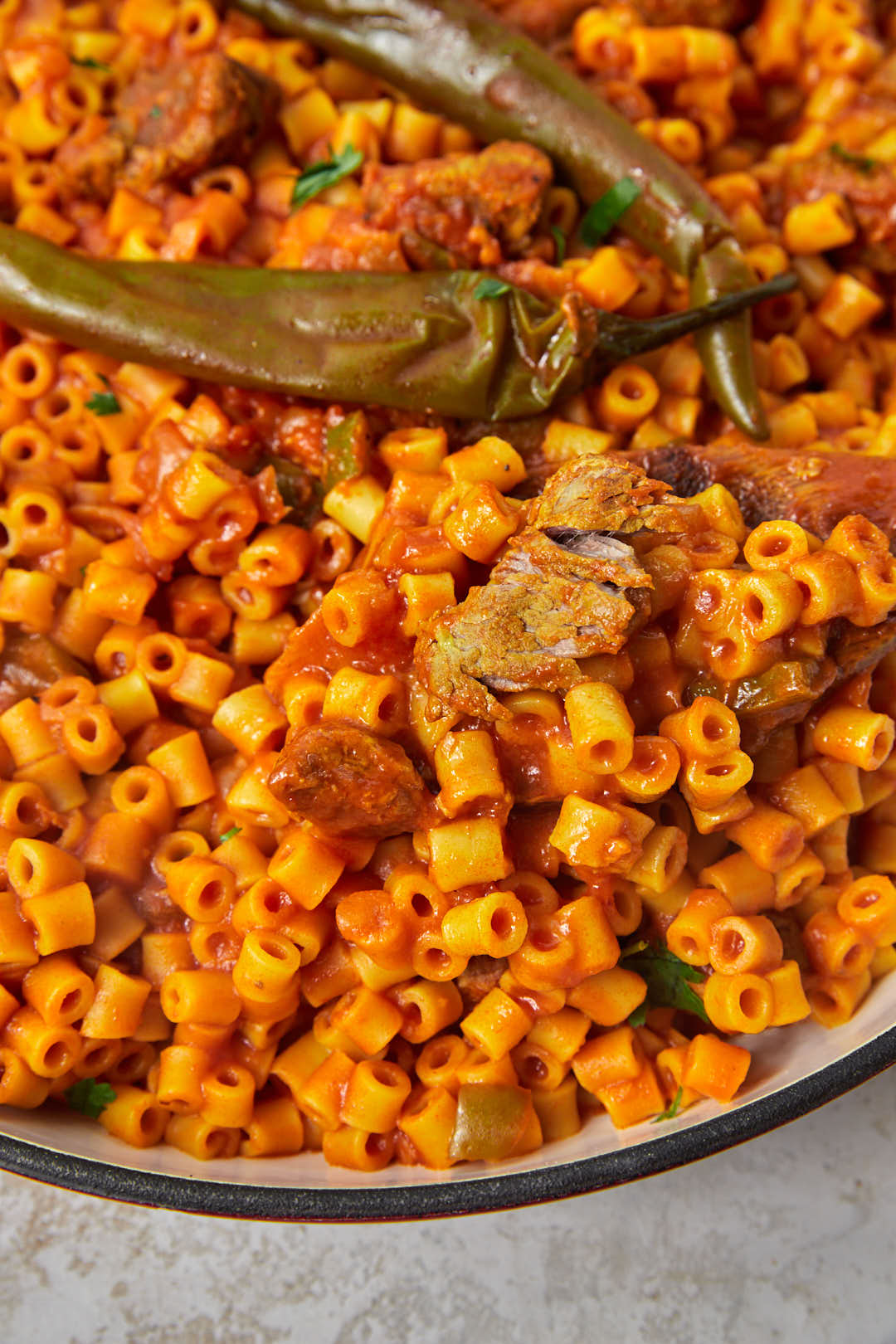 zoomed in photo of Libyan pasta with some meat cubes being scooped out with a wooden spoon.