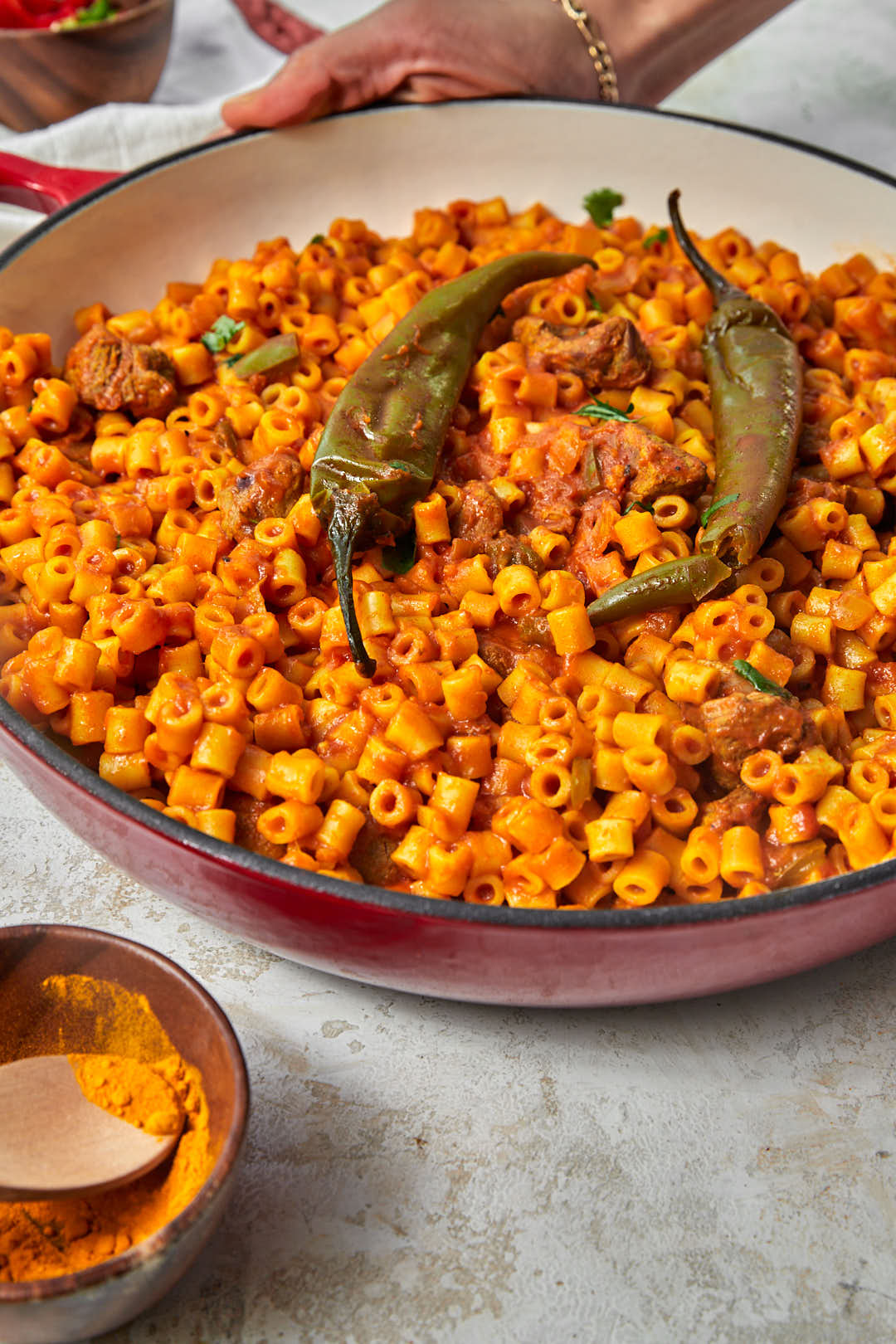 side shot of mbakbaka in a red skillet on a white background.