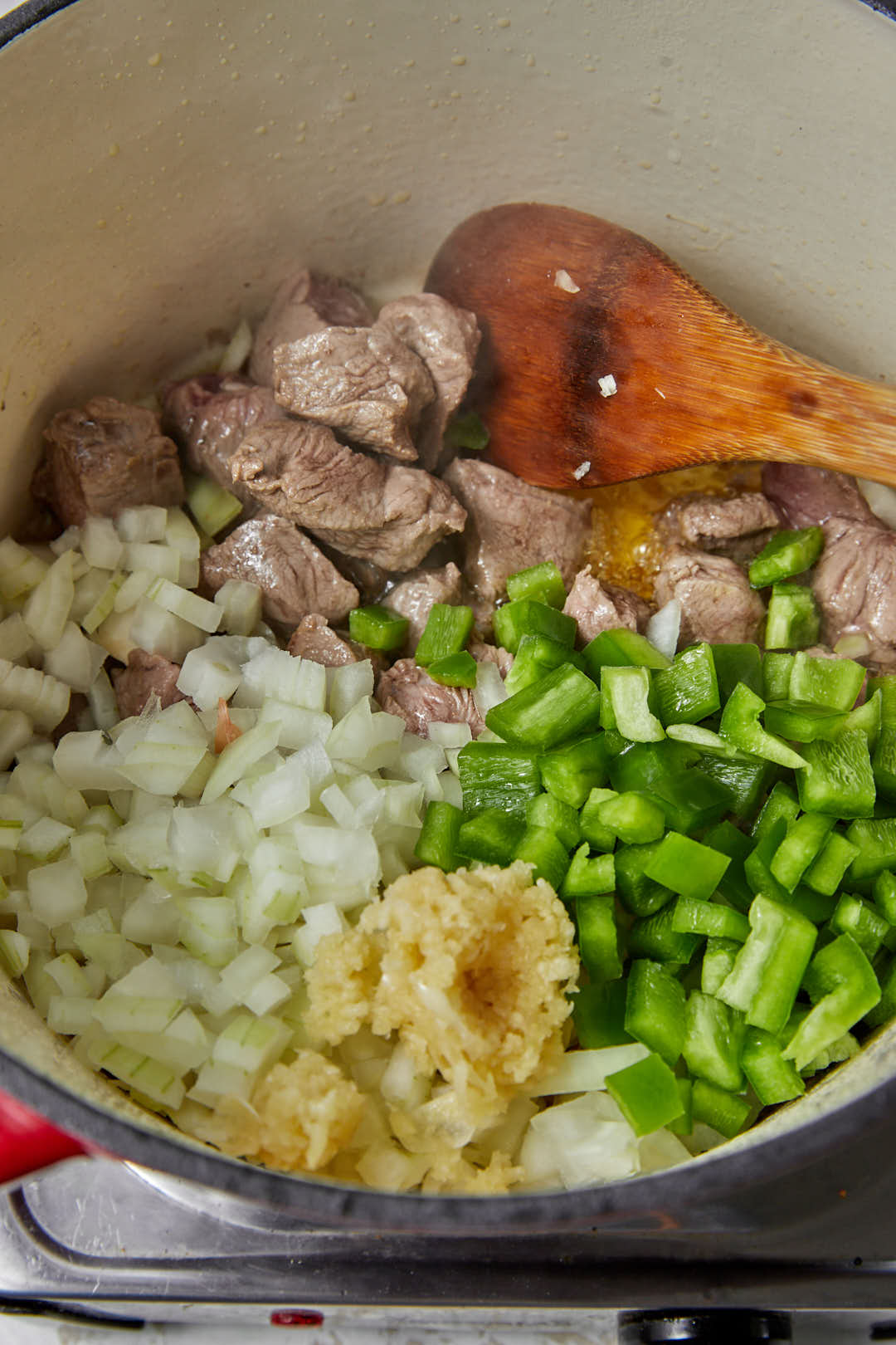 bell pepper, onion, and garlic added to browned beef cubes in a deep saucepan.