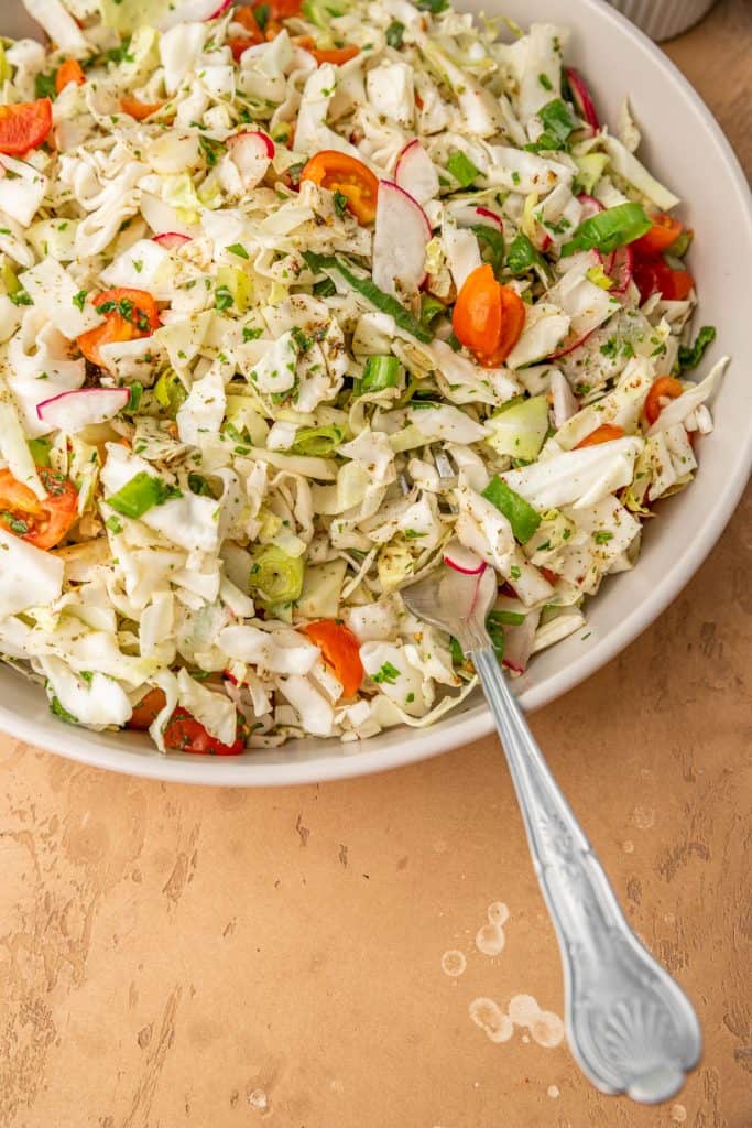 close up of lebanese cabbage salad with a spoon scooping some out