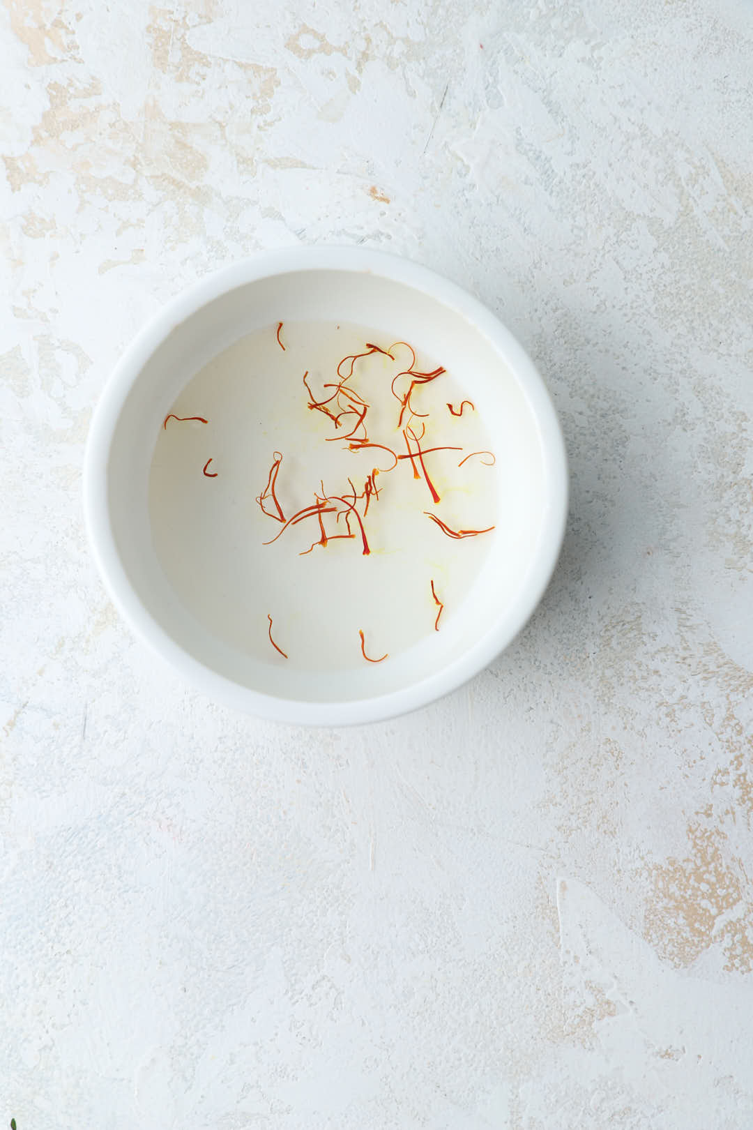 saffron threads in water in small white bowl.