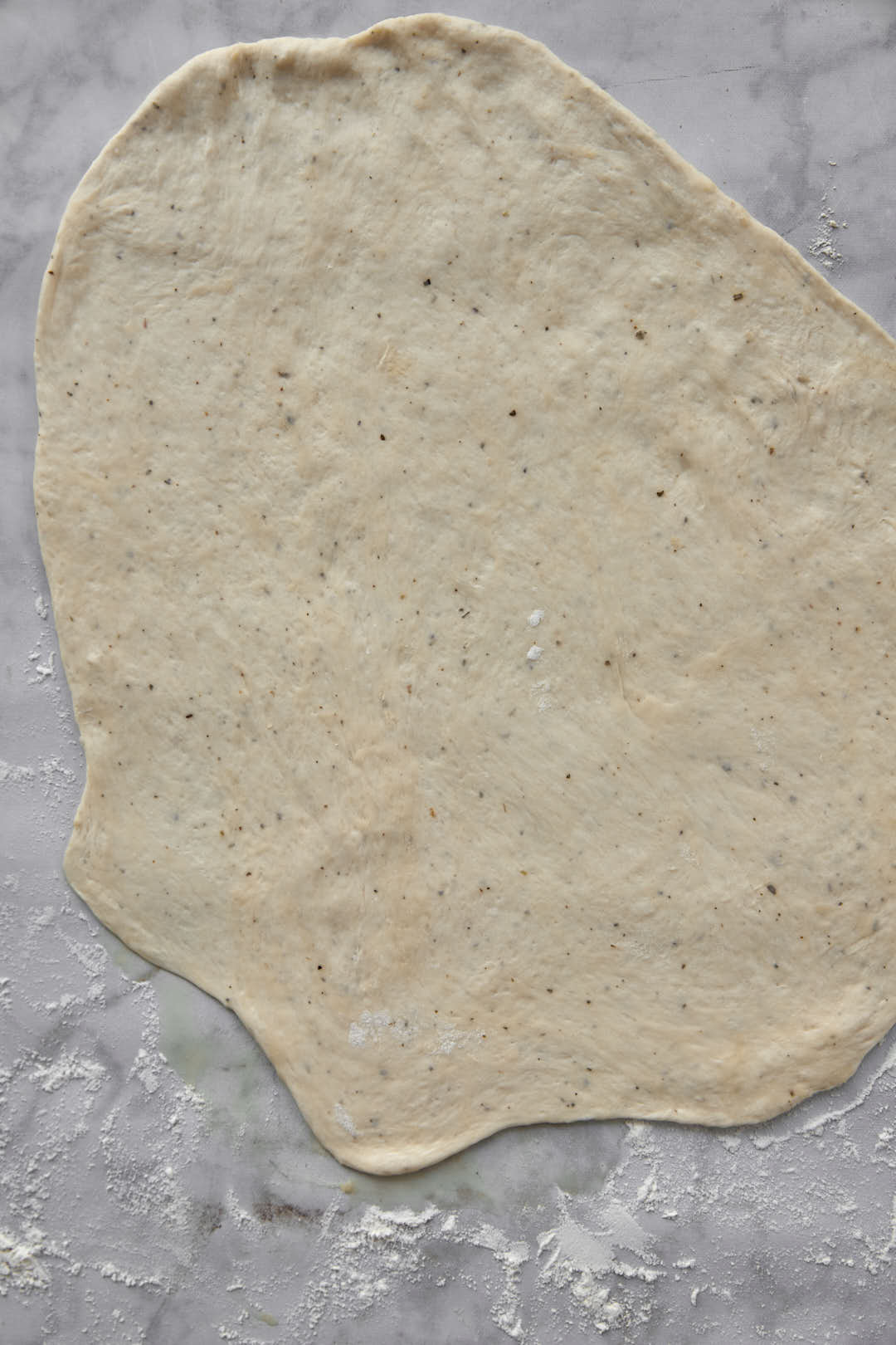 pizza dough rolled out very thin on floured white background.
