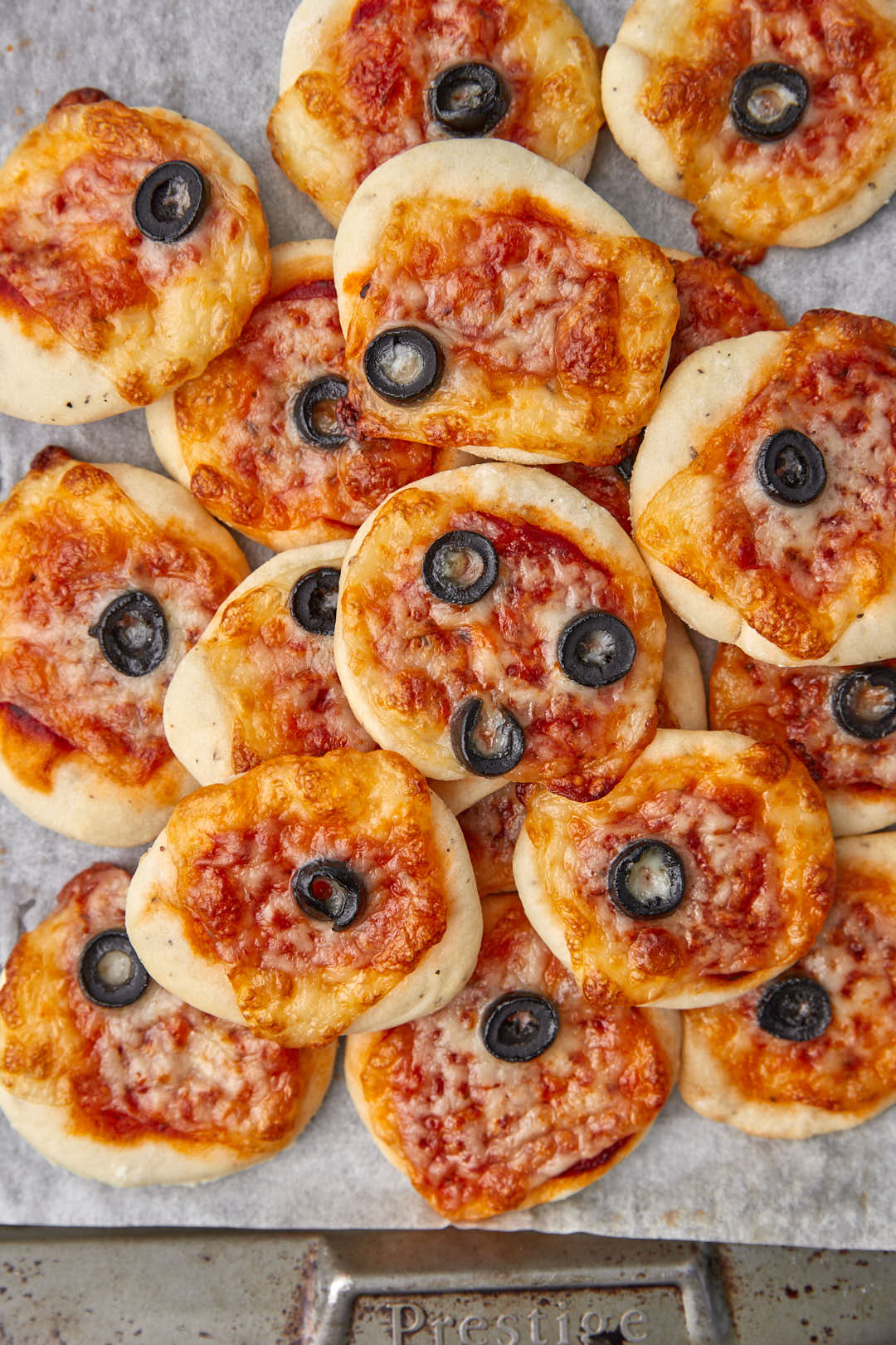mini pizzas with olives on a baking sheet