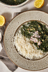 mulukhia in a bowl with a halved lemon on the side.