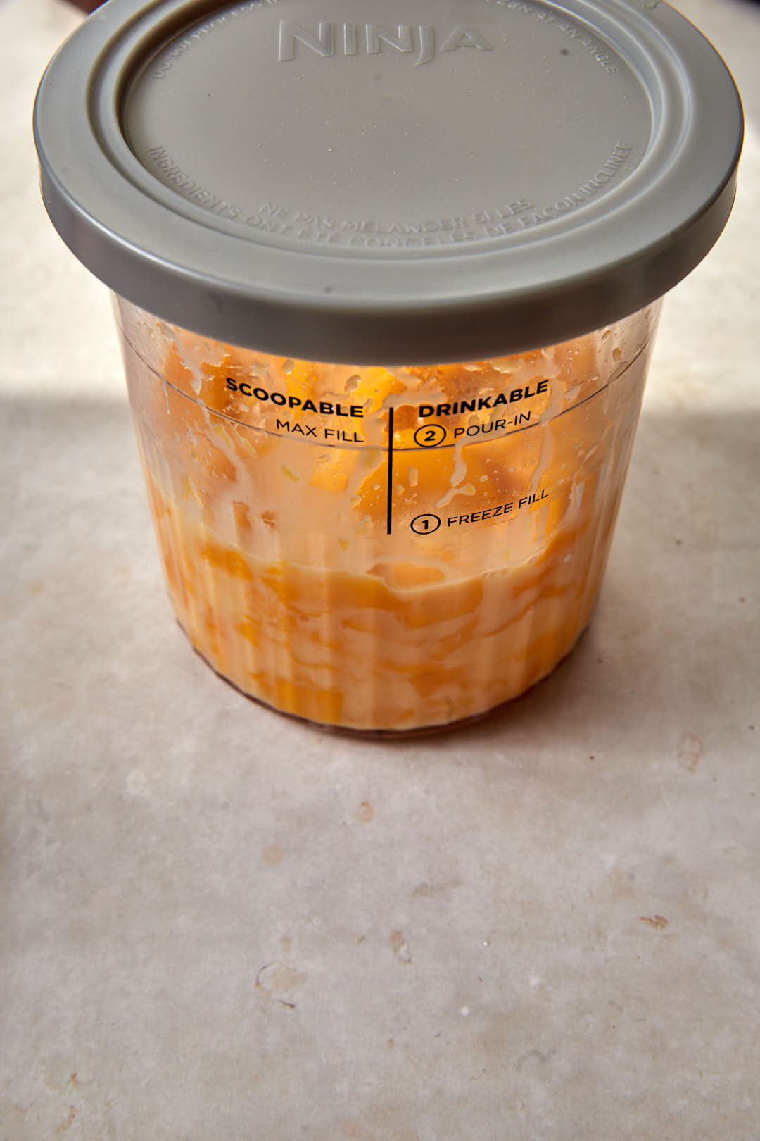 ninja creami pint covered with mango sorbet ingredients inside.