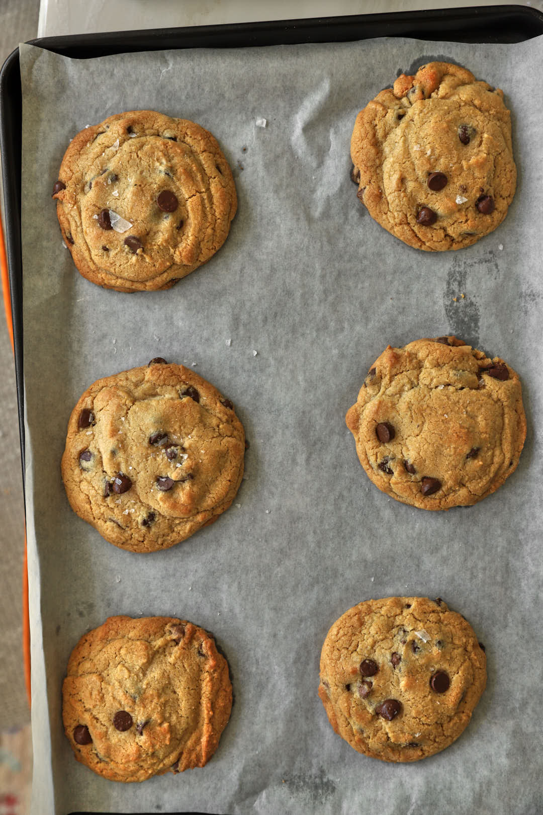 baked chocolate chip cookies on a parchment paper lined baking sheet.