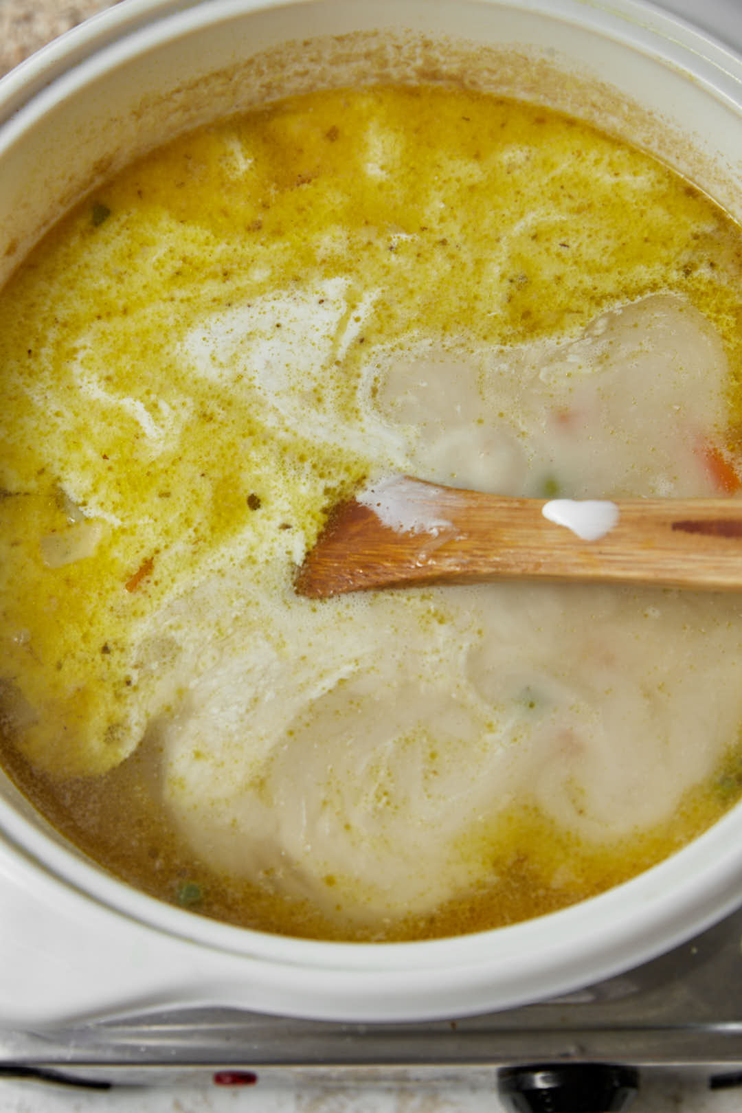 milk added to oatmeal soup in a white pot.