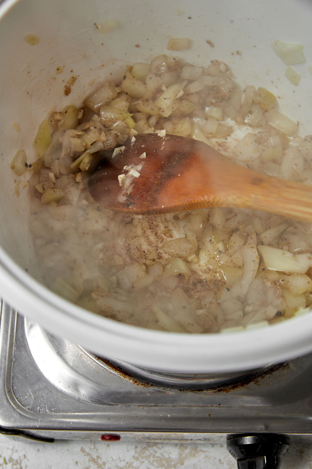 sauteed onions and spices in a white soup pot.