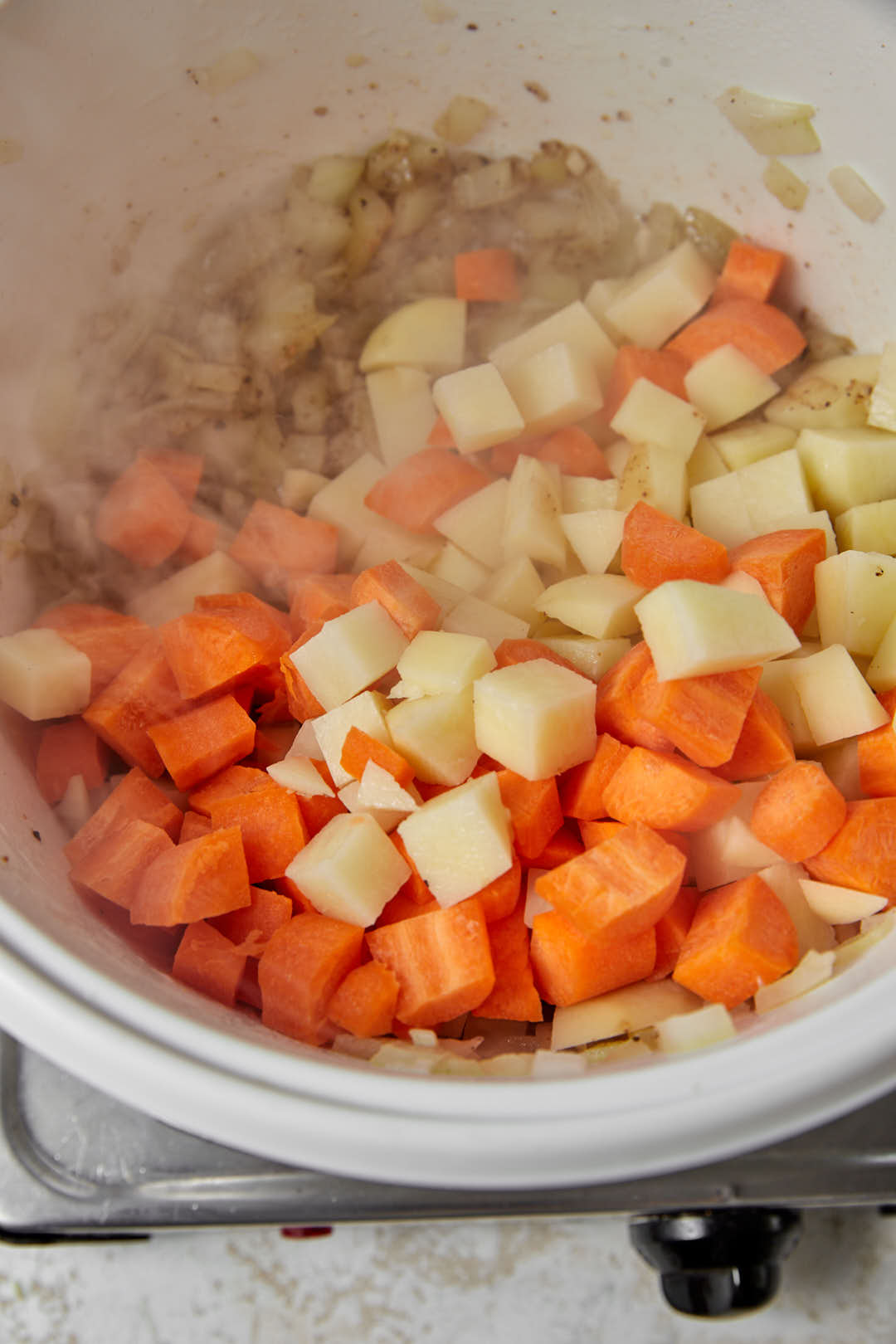 carrots and potato cubes in a white saucepan.